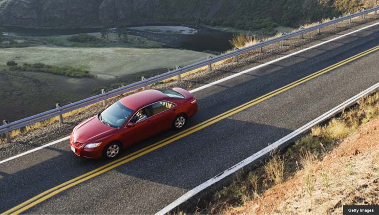 Red car on country road with view