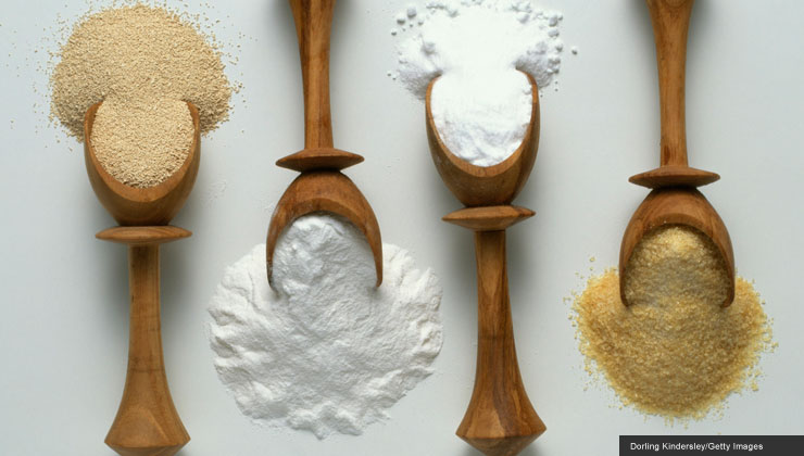 Four wooden spoons with various baking ingredients