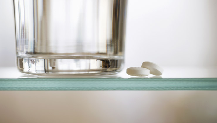 Medication and water glass on shelf