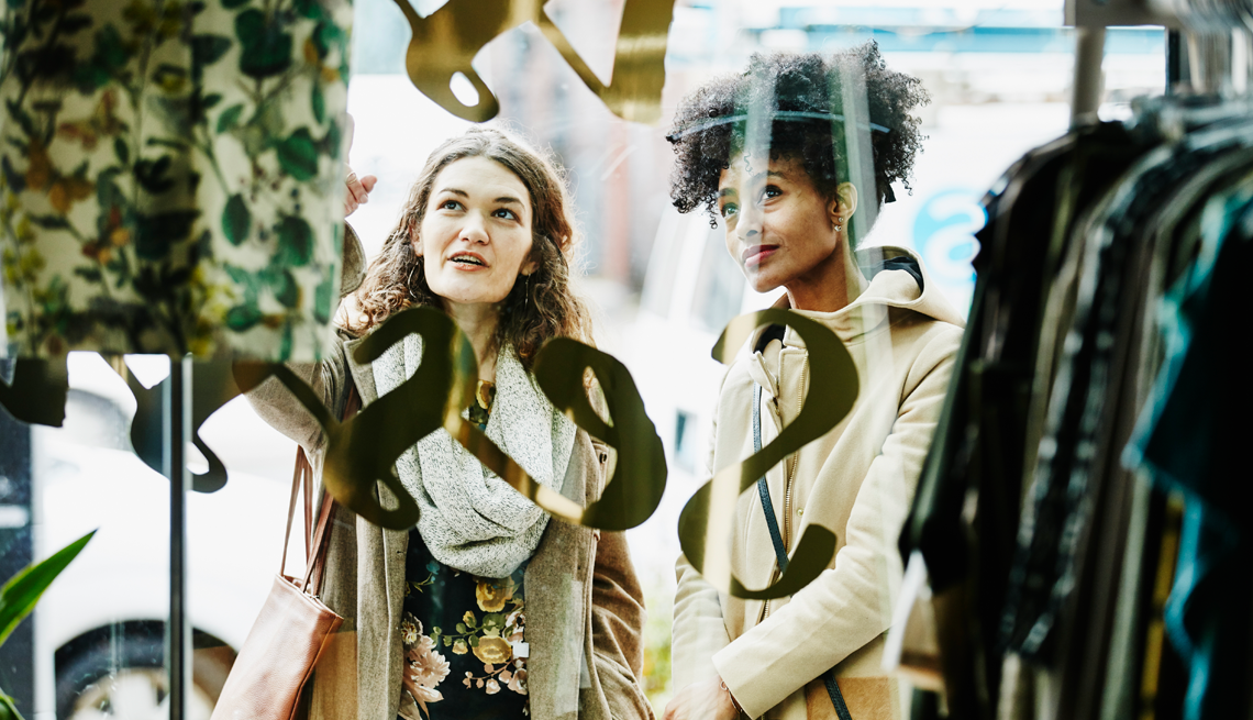 two women looking at dresses through a window