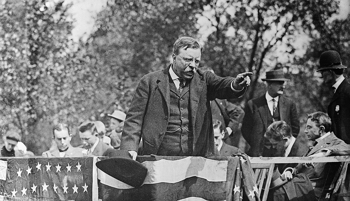 Theodore Roosevelt standing on a podium pointing into the crowd during a campaign rally speech. 