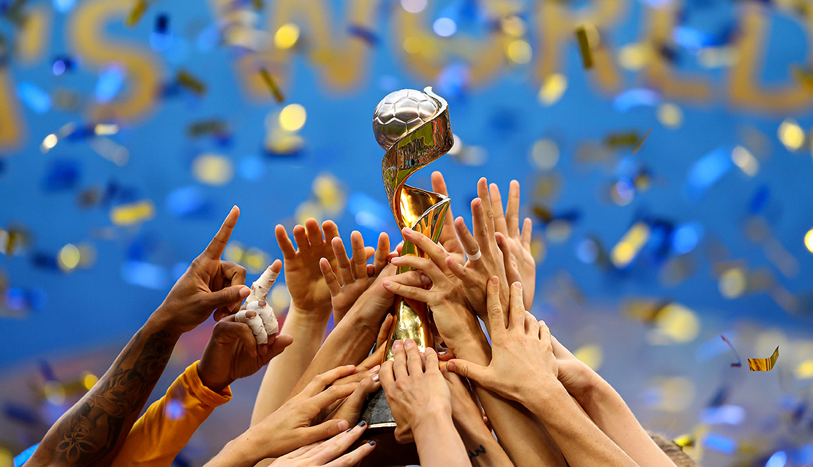 Women's World Cup hands reaching up to hold a trophy