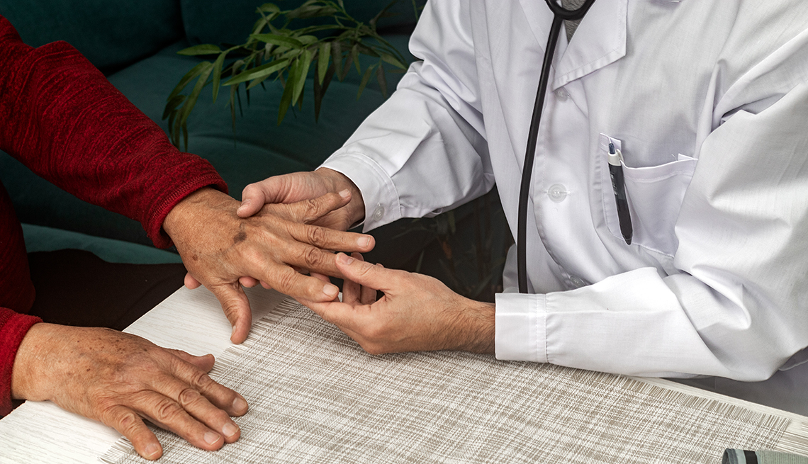 doctor examining the hand of a man. 