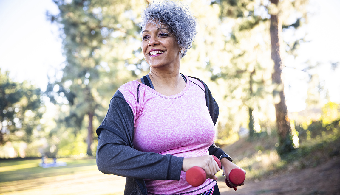a woman power walking with weights in a park a woman power walking with weights in a park