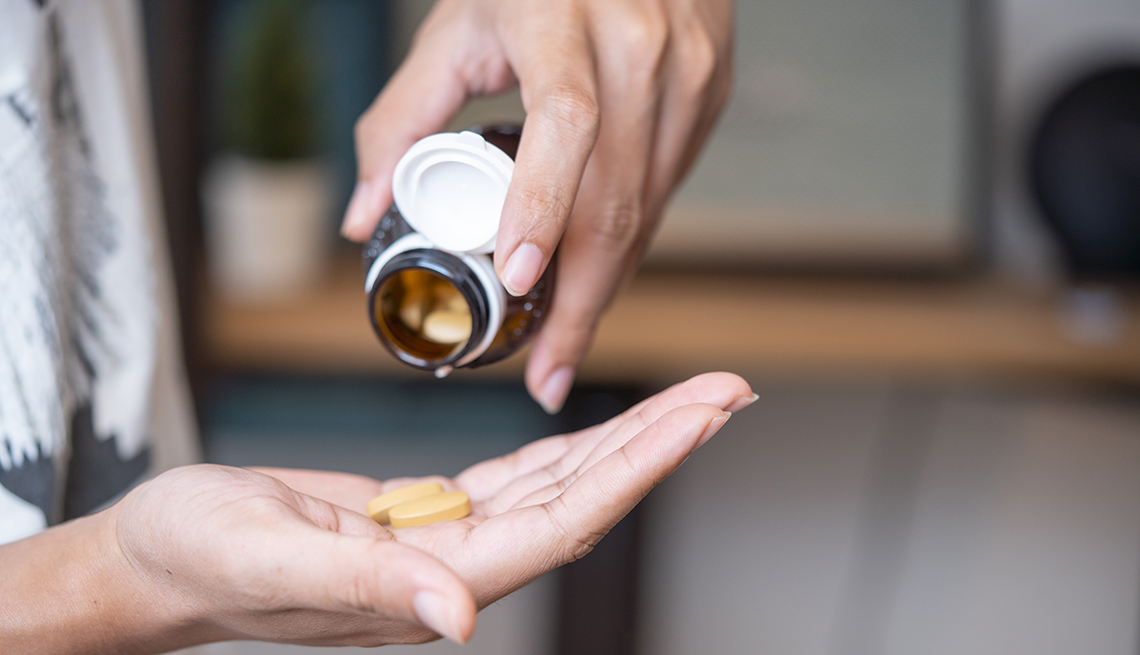 a person holding a pill bottle putting vitamins into their hand