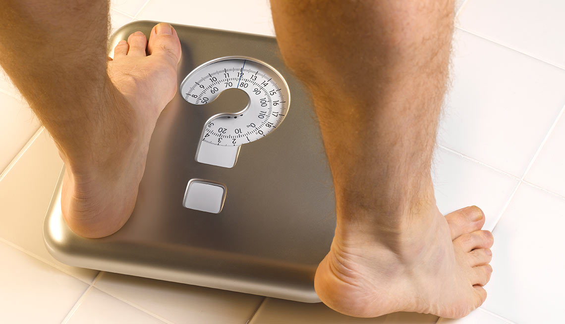 Man's feet stepping on scale that has a question mark on it Man's feet stepping on scale that has a question mark on it
