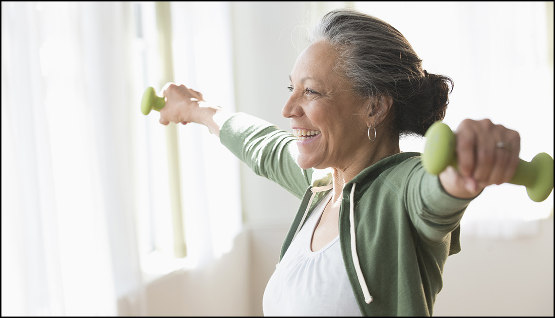 Older Hispanic woman lifting weights in living room Older Hispanic woman lifting weights in living room
