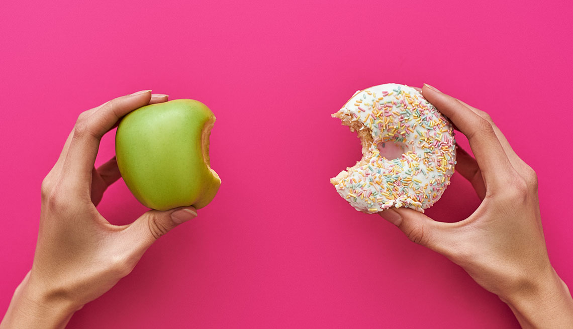 pair of hands, one holding an apple, one holding a donut