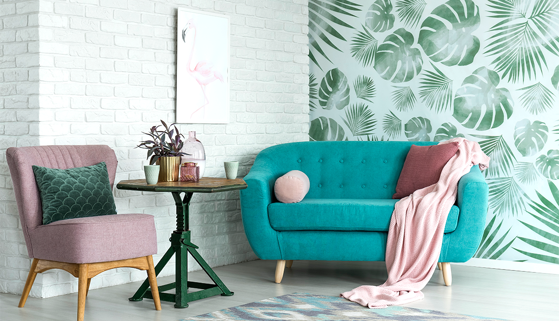 living room with leafy wallpaper accent rug plant and patterned throw pillow
