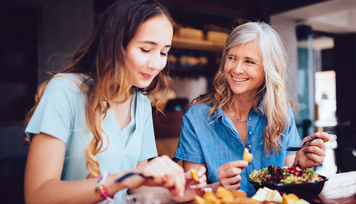 Coupons for Local Dining two women, older and younger, mom and daughter, sitting at restaurant bar counter, eating and smiling
