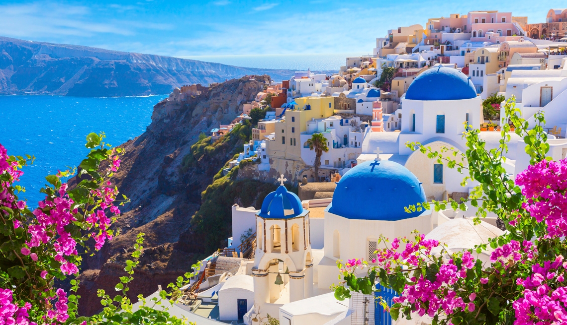 flowers in front of the domed blue and white buildings of santorini greece sitting over the agean sea flowers in front of the domed blue and white buildings of santorini greece sitting over the agean sea
