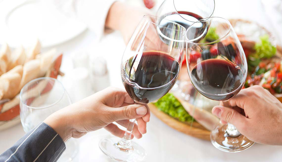 Dos personas brindan mientras toman vino Dos personas brindan mientras toman vino