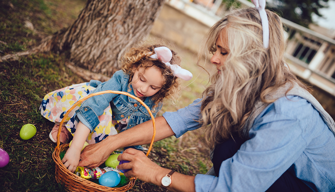 Abuela con su pequeña nieta recogen huevos de pascua