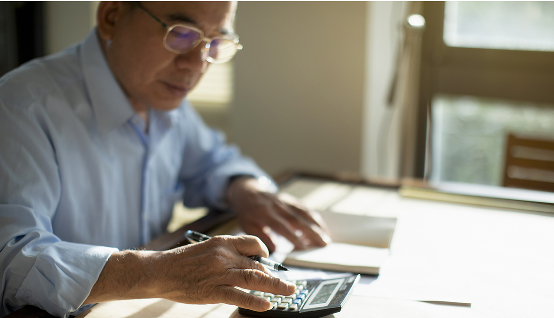 Hombre hace cuentas en una calculadora y apunta en una libreta