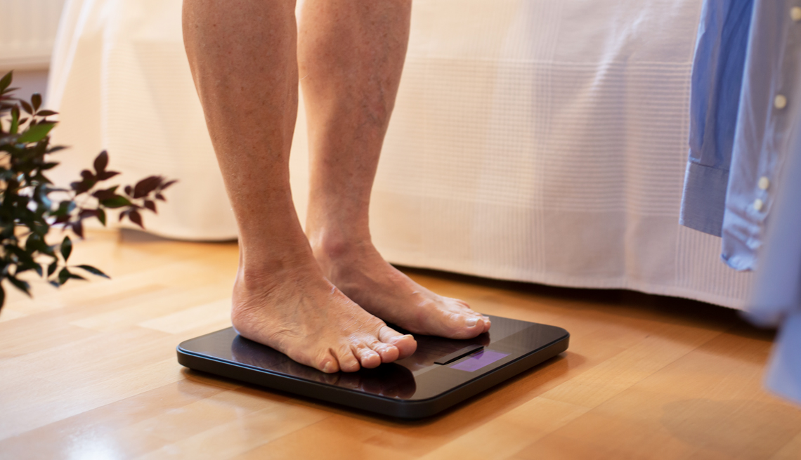 Un hombre se pesa en una balanza