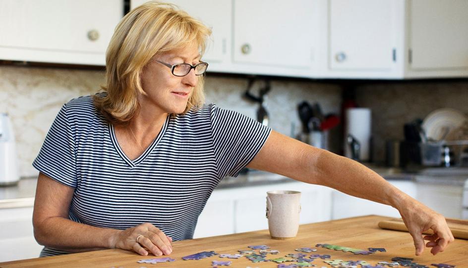 Una mujer arma un rompecabezas en su cocina