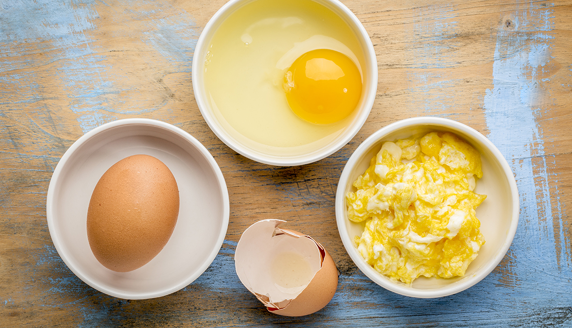 Huevos crudos y revueltos sobre una mesa de madera