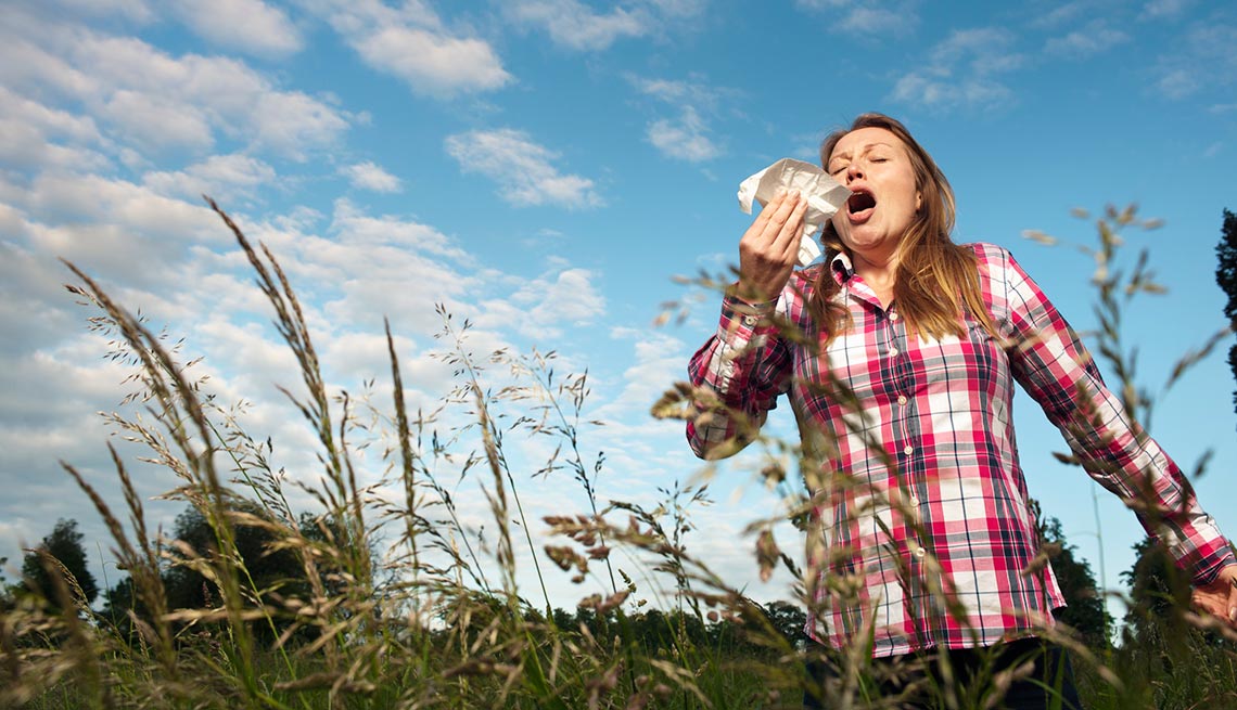 Mujer al aire libre en un campo abierto estornudando - Alergias de temporada Mujer al aire libre en un campo abierto estornudando - Alergias de temporada