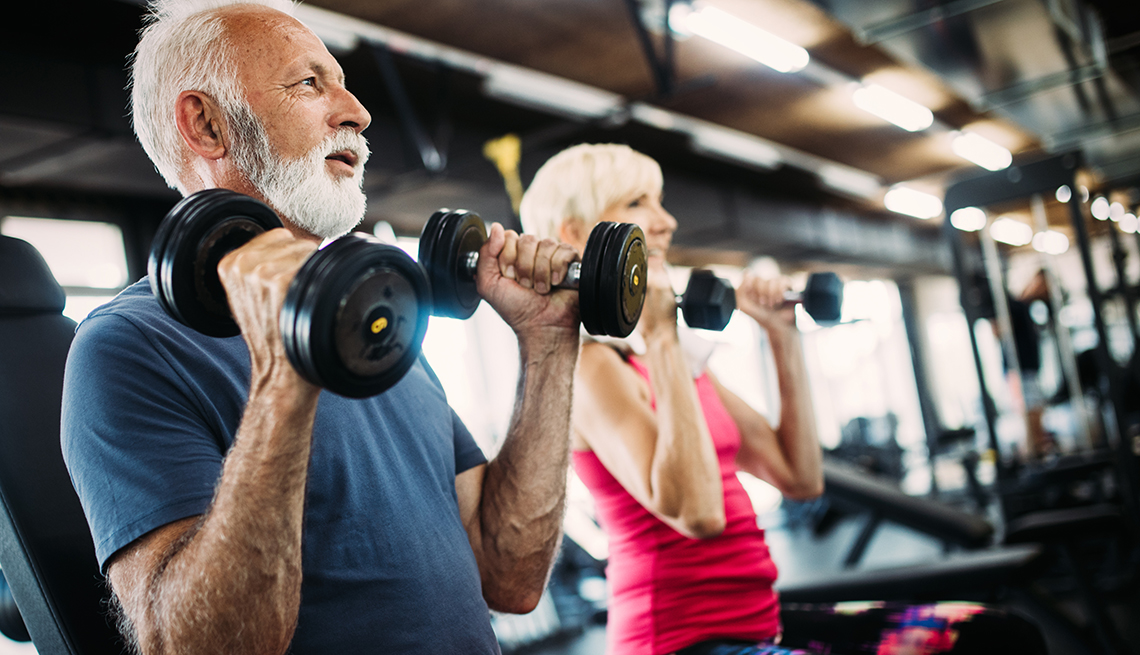 Un hombre y una mujer levantan pesas en un gimnasio