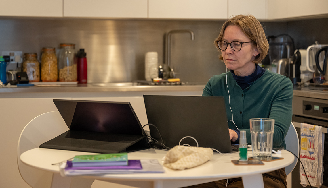 Mujer con dos computadoras en la cocina de su casa durante la pandemia.