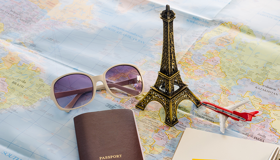Pasaporte, lentes oscuros, réplica de la Torre Eiffel y avión a escala sobre un mapa Pasaporte, lentes oscuros, réplica de la Torre Eiffel y avión a escala sobre un mapa